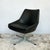 Swivel armchair with bucket seat construction and wraparound back. The molded seat shell is upholstered in black vinyl...
