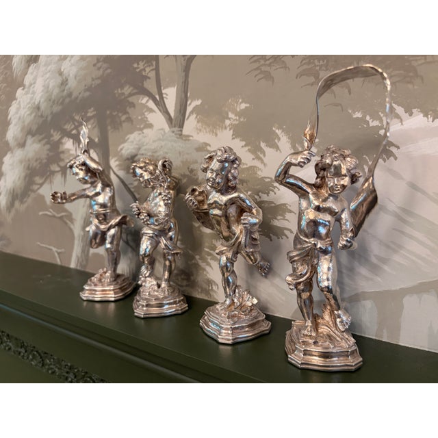 A lovely and whimsical set of four frolicking figures of a young Bacchus on stepped and chamfered bases. One figure is...
