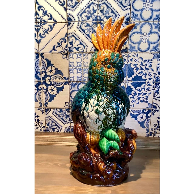 This intake, yet beautifully bright ceramic parrot cockatoo bird sitting upon a perch has been glazed in blue, green,...