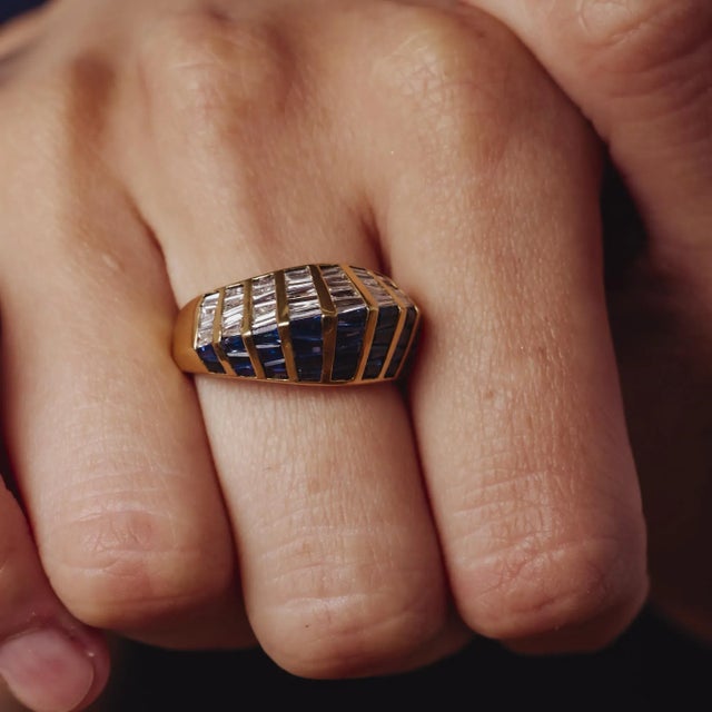 This striking vintage 2000’s 18k yellow gold ring features 2.12ct of vivid tapered baguette sapphires accented by 1.15ct...