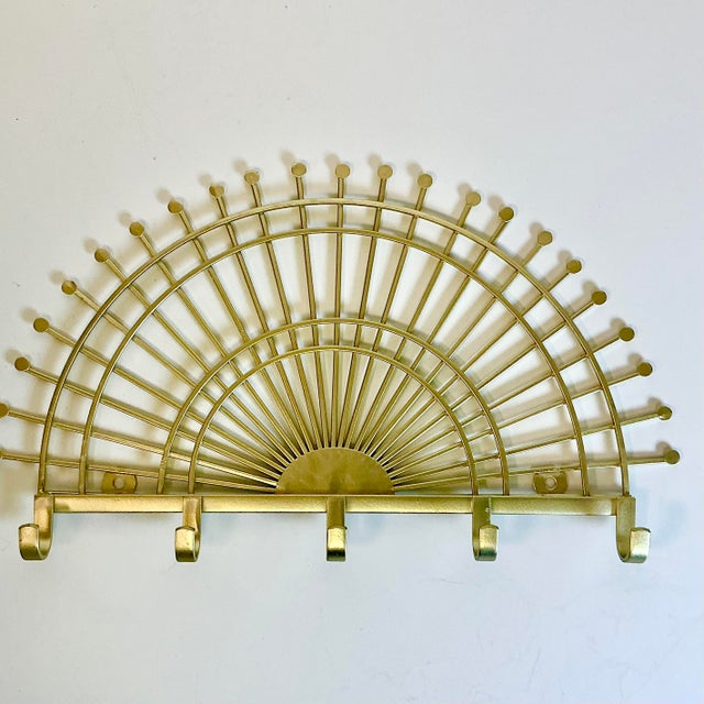 This is a lovely Wall Hook designed in a matte gold Sunburst. It has 5 hooks and the sun rays are capped with dots at the...