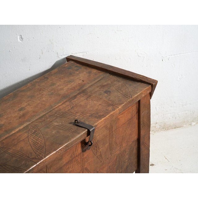 This antique carved trunk in pine wood features a flat geometric carving with diamond and stylised branch motifs covering...