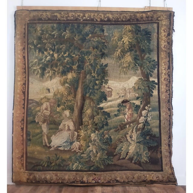 Aubusson tapestry dating from the early 18th century depicting figures and a dog in an architecturally designed green...