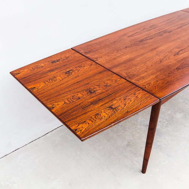 Vintage boat-shaped draw leaf dining table in Brazilian rosewood, made in Denmark c. 1960s. The bowed edge, tapered legs,...
