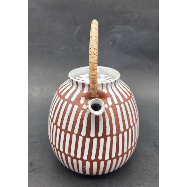Offered is a red clay striped glazed porcelain tea pot with a wicker handle created by Edith Nielsen in Denmark in the...