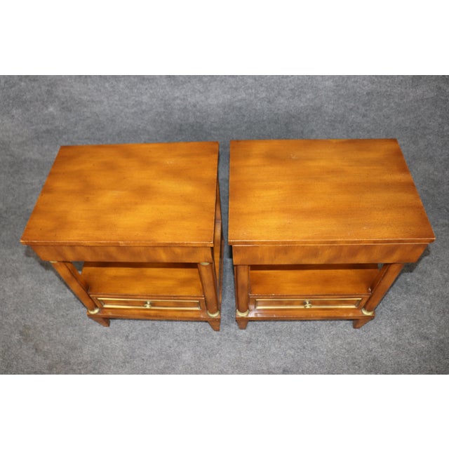 An elegant and highly versatile pair of Directoire-style two-drawer nightstands, beautifully executed in warm walnut and...