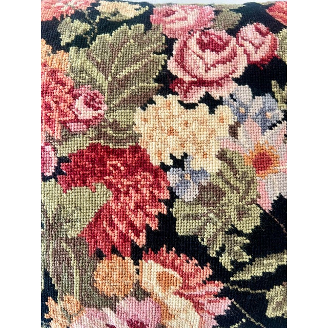 This vintage needlepoint pillow features a floral motif that covers the entire front side of the pillow. The background of...