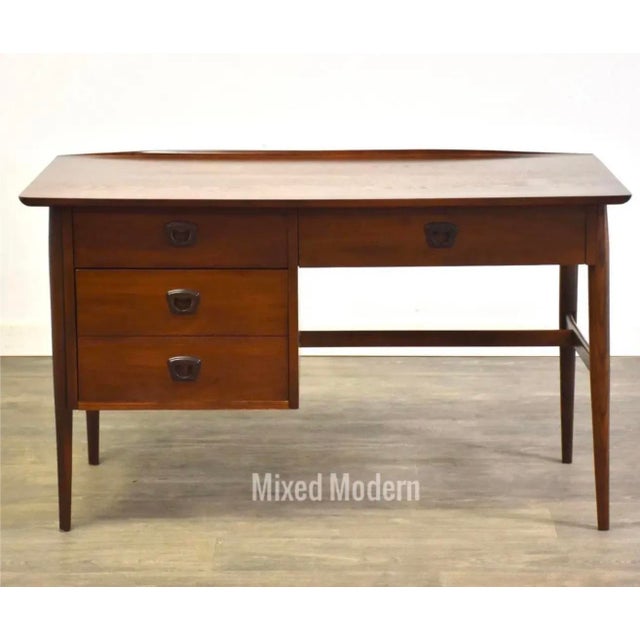 A mid century modern walnut desk with a lipped top and a drawer capable for holding files. Professionally refinished. Made...
