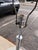A striking mid-century modern floor lamp with an integrated circular glass table, featuring a sophisticated combination of...