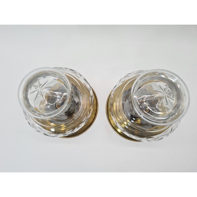 A pair of elegant Mid-Century Modern-style wall sconces, made of brass and transparent, hand-cut glass. The sconces most...
