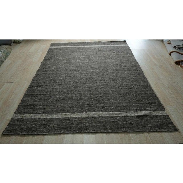 This hand woven wool rug features a primary gray color palette and a flat-weave structure typical of authentic Kilim...