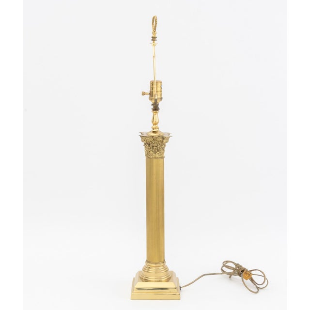 Neoclassical Style Gilt Metal Corinthian Column Table Lamp, the fluted column above a square base and surmounted by a hand...