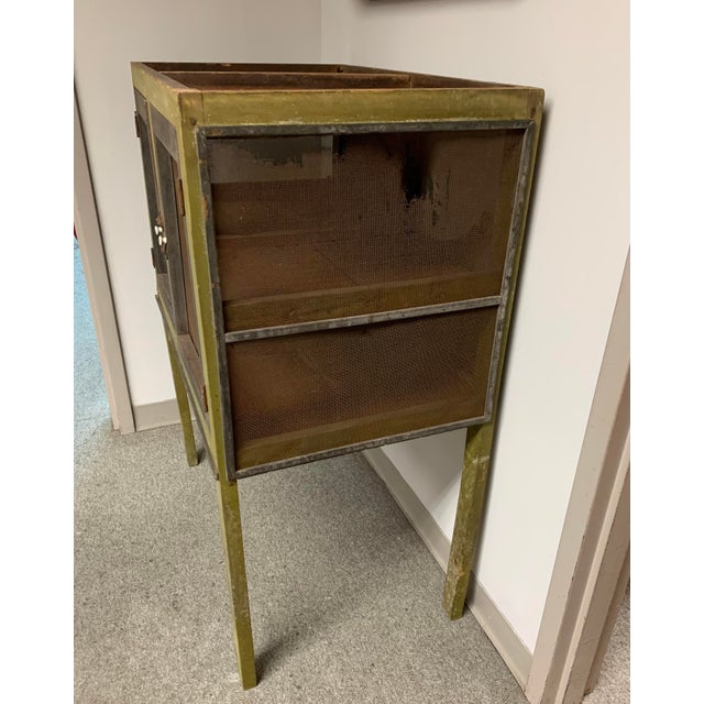 Rustic primitive antique kitchen pie safe with avocado green and black paint and worn wire screening. One leg has been...
