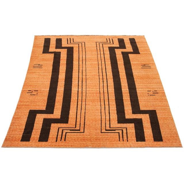 This hand-loomed modern wool rug is truly captivating. Its vibrant orange background is the perfect canvas for the...