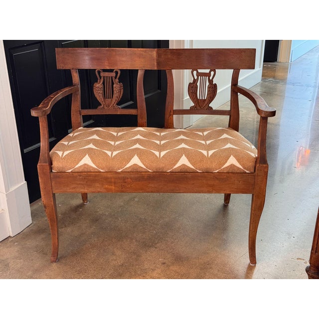 A small French settee in walnut, the flat crest rail above two openwork splats carved as lyres, each flanked by swans with...