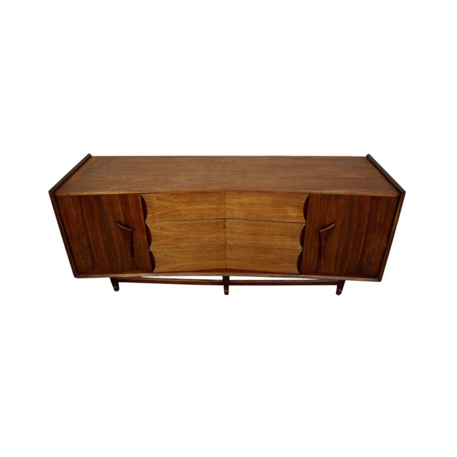 This mid-century walnut dresser is made by Specialty Woodcraft Inc.. The piece has an almost sculptural construction with...