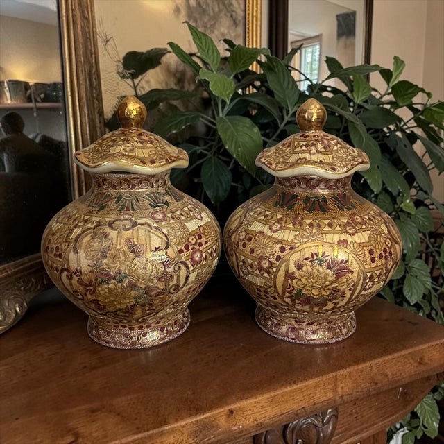 A stunning pair of vintage porcelain lidded temple jars showcase the exquisite artistry of Japanese Satsuma. They feature...