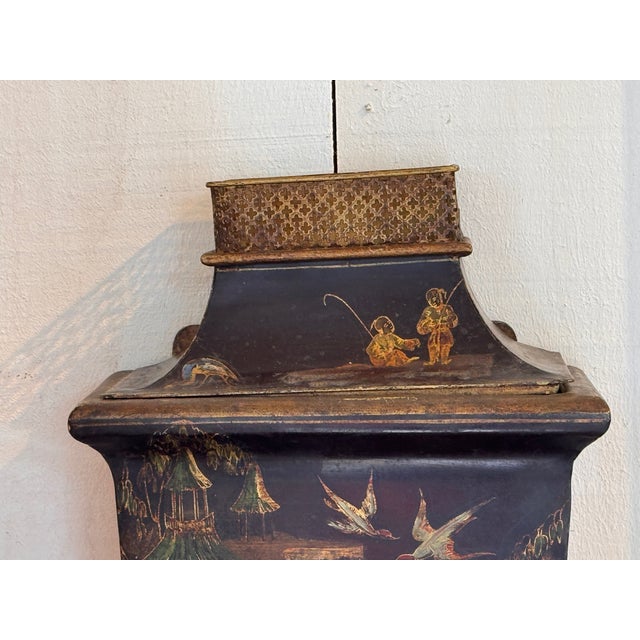 A painted tole wall lavabo comprised of an upper cistern and lower basin. The black ground is decorated with chinoiserie...