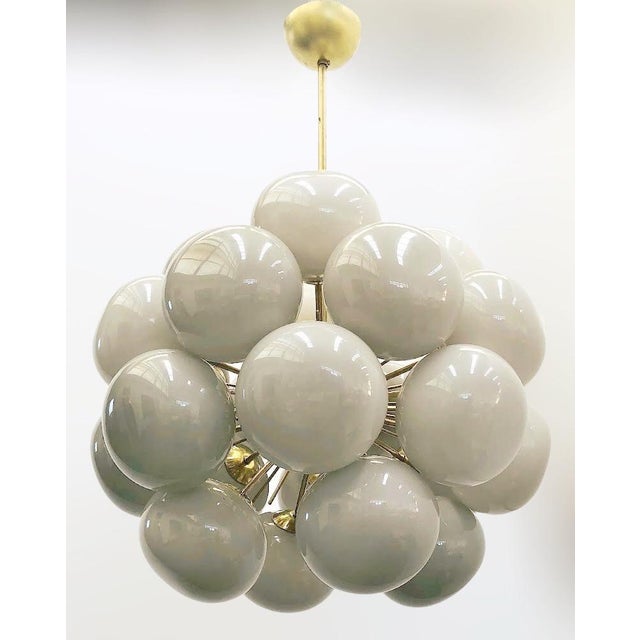 Italian sputnik chandelier with 24 cream Murano pebble glass shades mounted on brass frame in unlacquered natural brass...