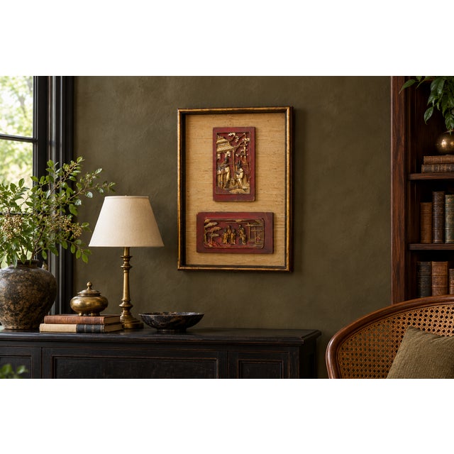 Two carved panels in red and gilt, mounted together in one gilt shadow box over natural grasscloth. One panel runs...