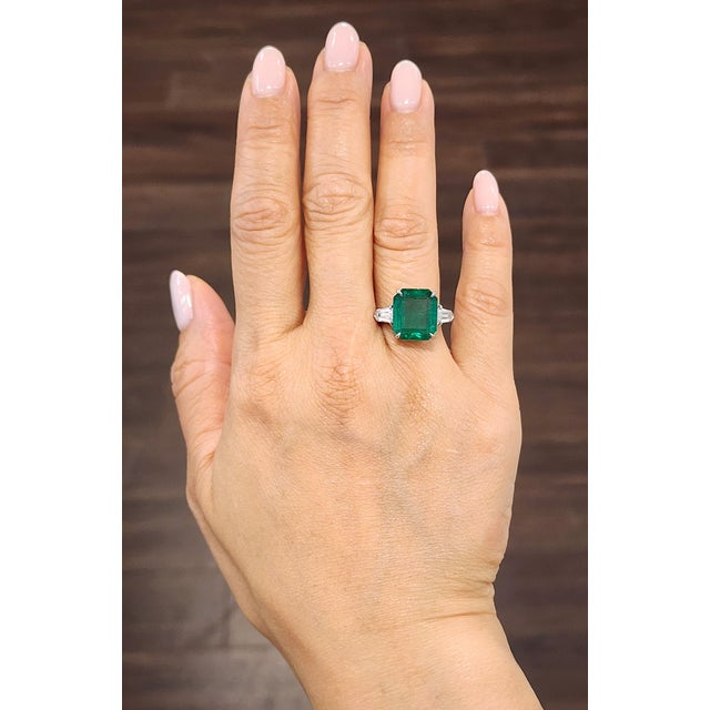 This striking cocktail ring showcases a 6.89-carat GIA certified emerald-cut emerald, radiating a vivid green hue....