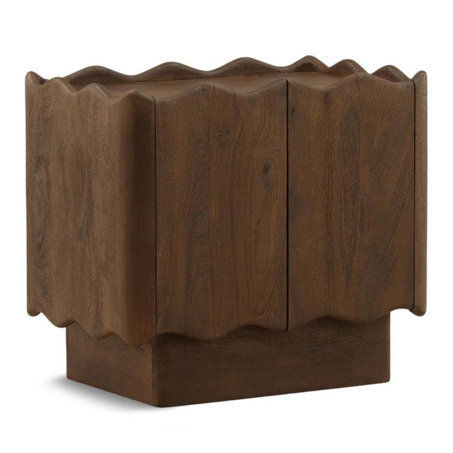 Sculptural solid mango wood nightstand with deeply carved wave-front facade and rich brown wood tones. The rhythmic,...