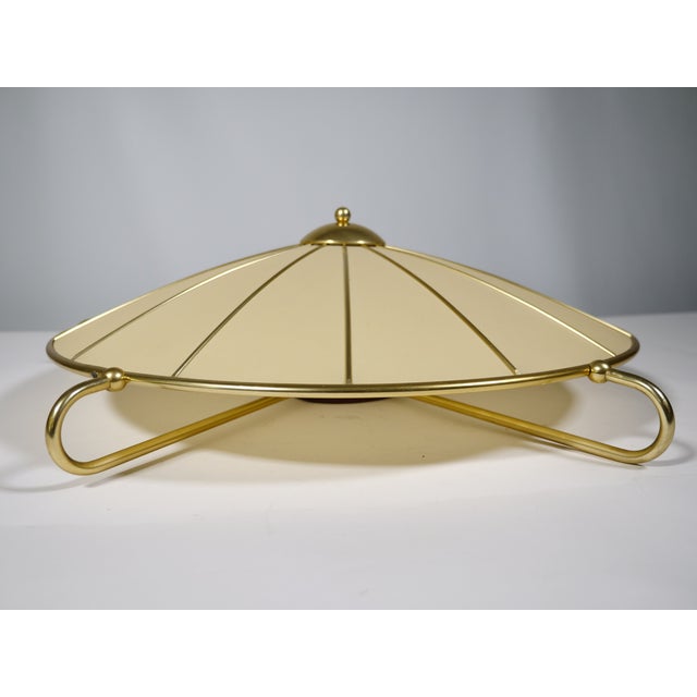 Large, three-light ceiling lamp by Erco with a flat, fabric-covered shade and radially structured metal frame. Brass-...