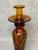 Slender candlestick made of hand-blown art glass in amber tones with a decorative dark pattern. The sculptural form and...