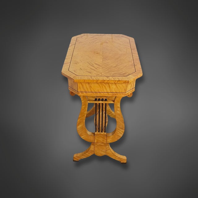 A beautifully crafted lyre-shaped side table in the Biedermeier style, veneered in flamed birch. The light, warm wood tone...