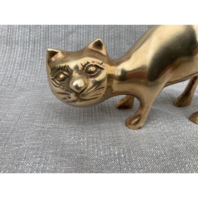 Mid century polished, brass cat figure, standing while stretching its back, with clean rounded lines and distinct facial...