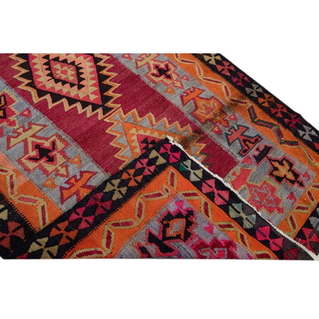 Beautiful kilim handmade wool runner with a red field. This Vintage flatweave rug has orange, gray, and tan accents...