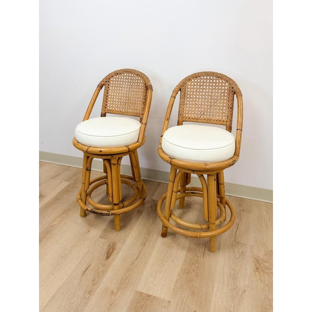 This pair of vintage rattan swivel counter height barstools brings a breezy, Hollywood Regency sensibility to any bar or...