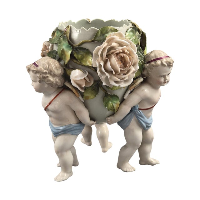 An elaborate late Victorian Sitzendorf porcelain centrepiece formed as an egg-shaped vase supported by three winged putti...