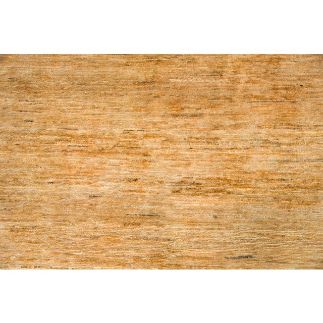 A stunning vintage late 20th century Afghani hand-knotted rug with a solid colored field woven in varying shades of golds...