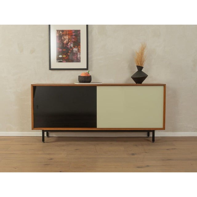 A classic sideboard by Lothar Wegner from the 1960s. High-quality walnut veneer body with two glass sliding doors in black...