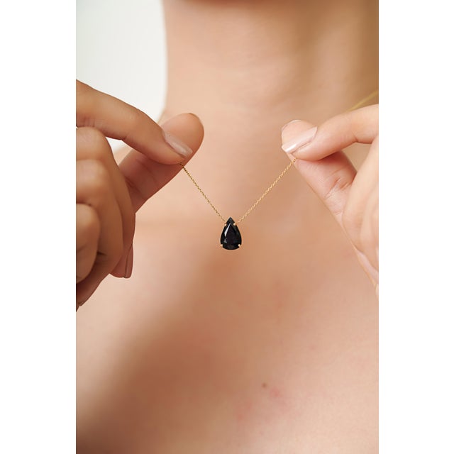 This solitaire pendant necklace features a 3.22 carat pear-cut black diamond set in 14k yellow gold. The diamond messuring...