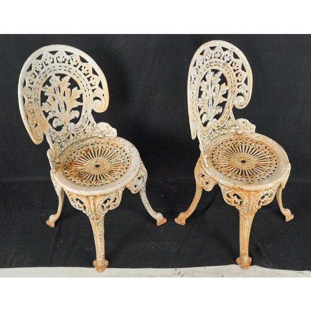 Victorian style patio garden chairs made of white painted cast iron. They feature a highly ornate foliate leaf pattern on...