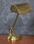 Bankers brass desk lamp, the shaped brass base, and pivoted sweeping arm supporting adjustable lampshade. The lamp has...
