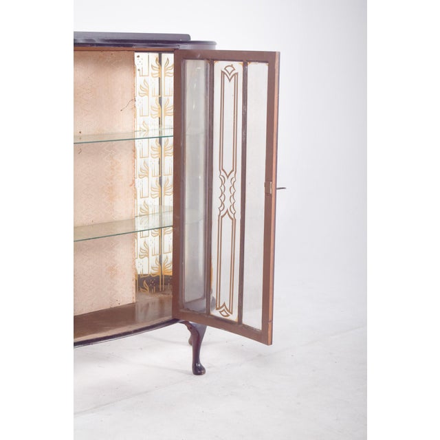 Display cabinet with curved legs. It stands out for its curved shape and elegant glass doors that reveal a carefully...