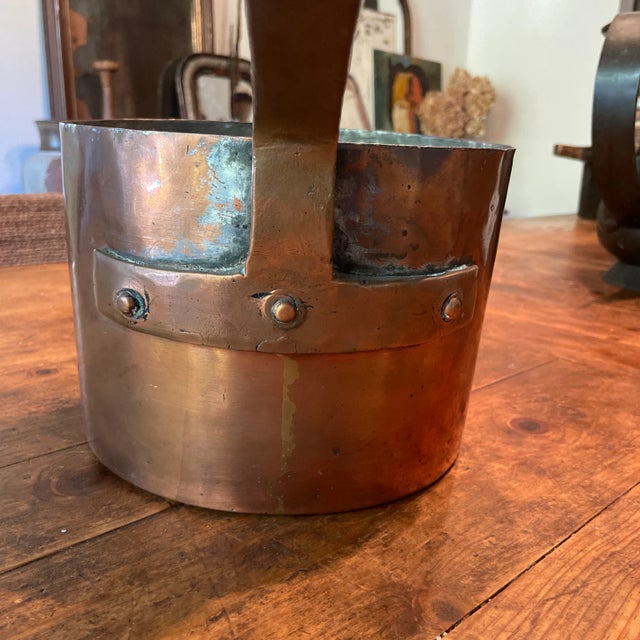 This is quite a pot! This handmade copper pot has lived many lives. The handle is riveted to the pot in beautiful form....