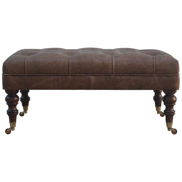 A luxurious ottoman upholstered in 100% buffalo hide leather with a deep buttoned top. Hand turned legs in light walnut...