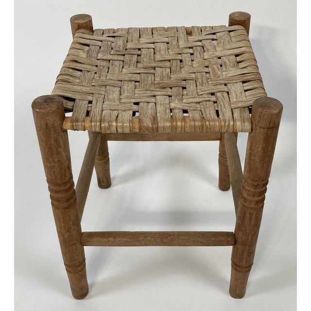 Antique square turned wood stool with woven rattan top. Nice detail to legs. Measures 15"H. Age wear. Sturdy.