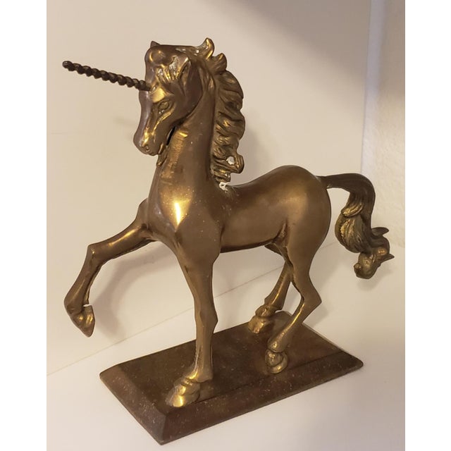A striking vintage brass unicorn sculpture by Enesco, dated 1982, presented in a beautifully sculptural prancing pose atop...