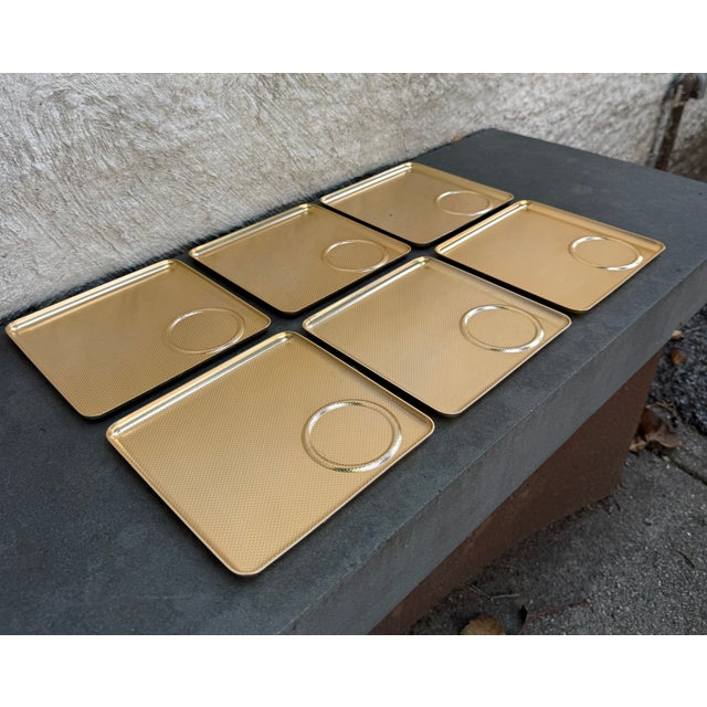 Set of six square embossed aluminum gold tone trays with coaster divot manufactured by Kaymet, UK. The model number is...