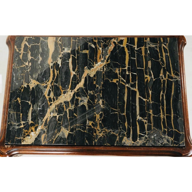 An instant showpiece, this richly detailed carved wood table is topped with a striking slab of black marble with dramatic...