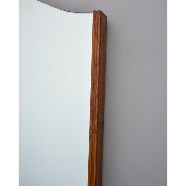 An elegant Italian wall mirror featuring a tall, vertical form with a distinctive serpentine-cut top edge — a graceful...