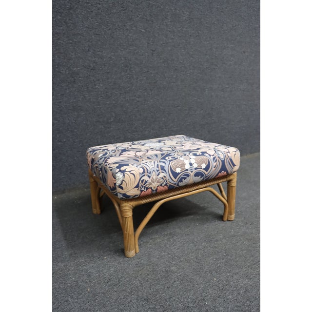 Split reed rattan ottoman featuring a woven frame with wrapped reed detailing and a generously padded upholstered seat....