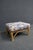 Split reed rattan ottoman featuring a woven frame with wrapped reed detailing and a generously padded upholstered seat....