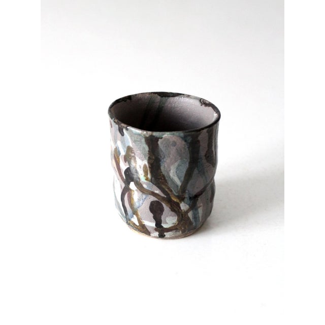 A vintage studio pottery vase with a softly shaped form and a layered, painterly glaze. Subtle charcoal, slate, muted...