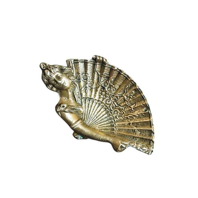 An authentic decorative piece from the late 19th or early 20th century, this delicate brass tray depicts the face of a...